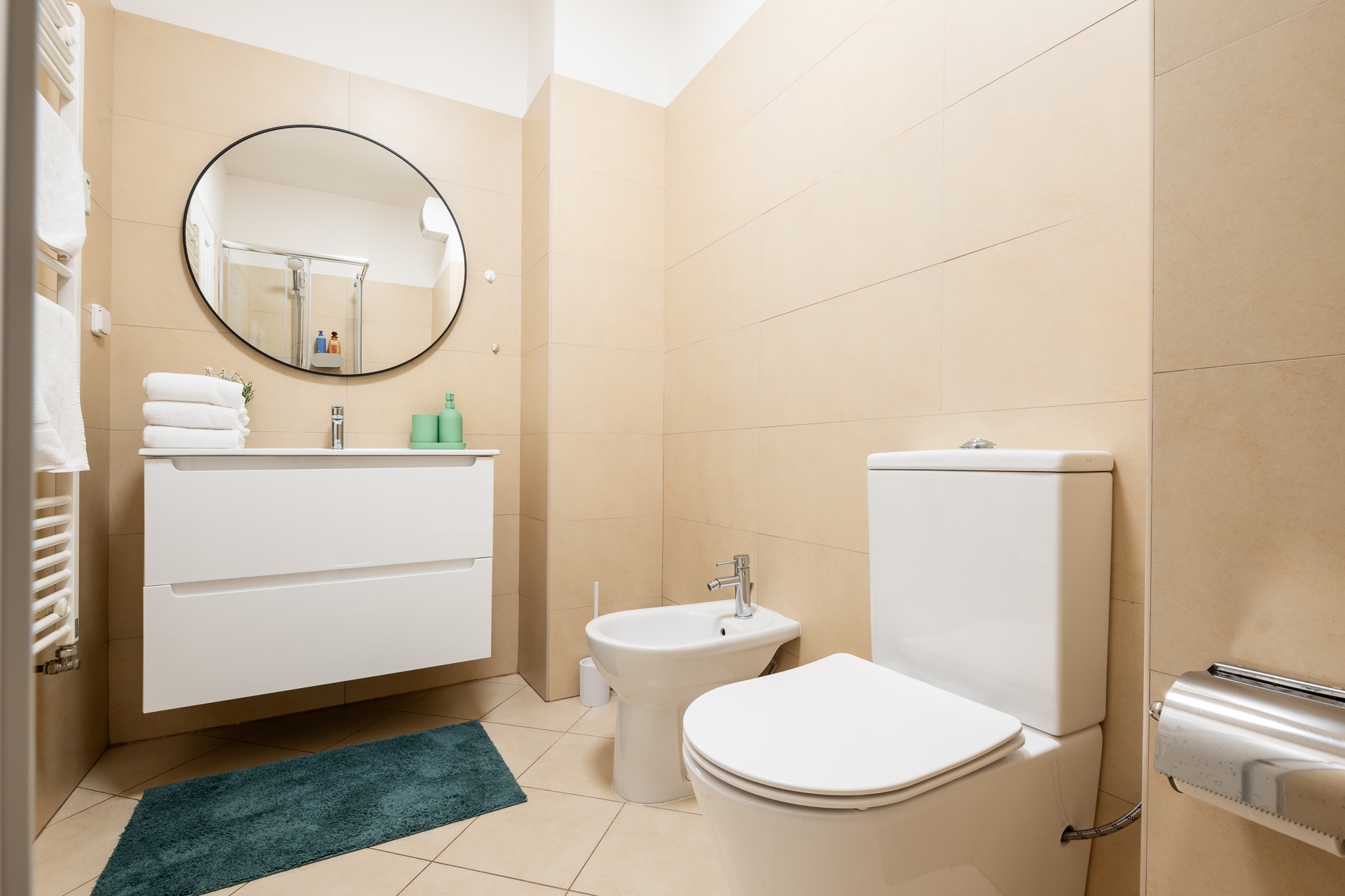 Letna71 bathroom with stone-toned tile and round mirror