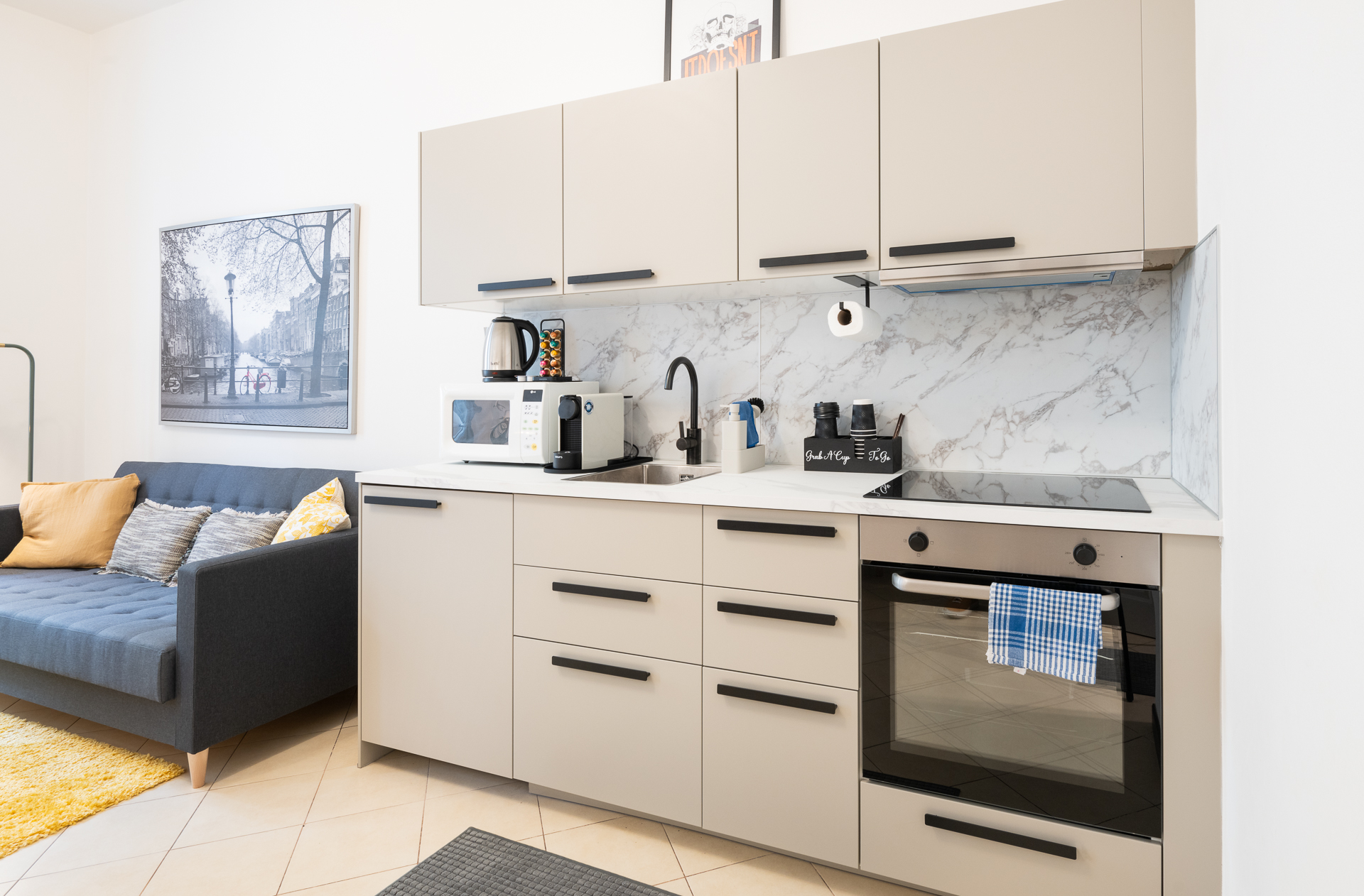 Bright Letna71 kitchen with warm cabinetry, oven and marble backsplash